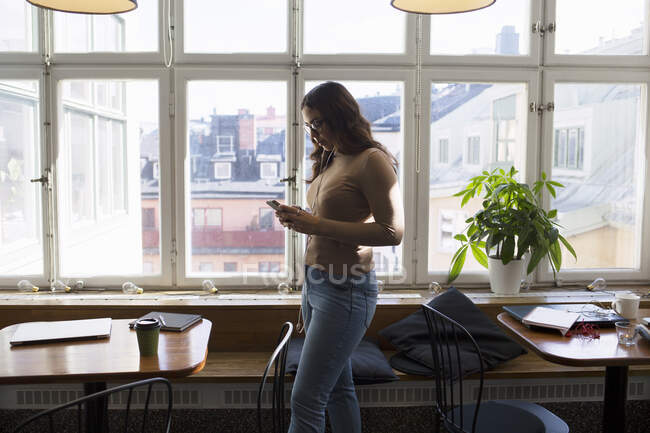 Young woman listening to music in office break room — Stock Photo