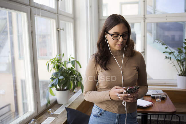 Mujer joven escuchando música en la sala de descanso de la oficina - foto de stock