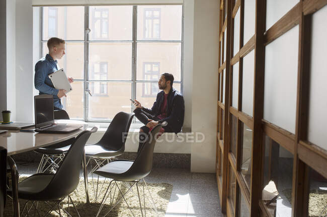 Молодые люди разговаривают в офисе — стоковое фото