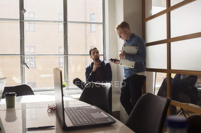 Молодые люди разговаривают в офисе — стоковое фото
