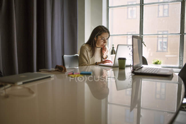 Mujer joven usando el ordenador portátil en la mesa de conferencias - foto de stock