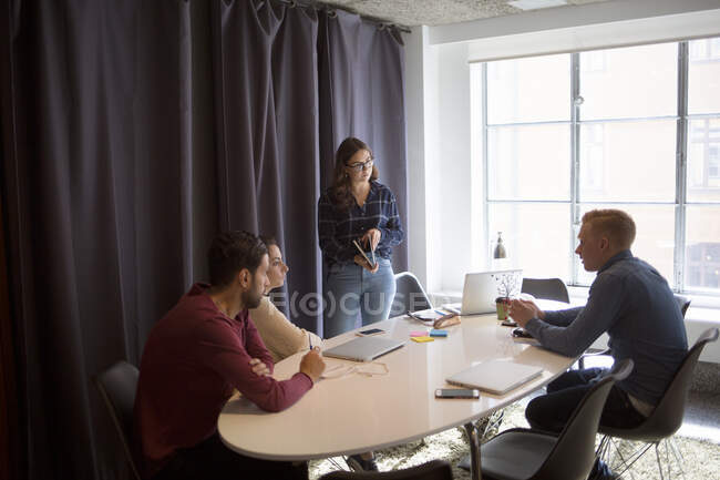 Compañeros de trabajo hablando en la sala de conferencias - foto de stock