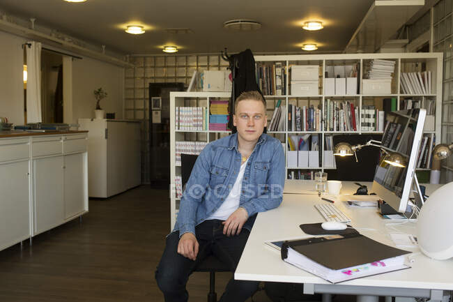 Jovem sentado à secretária no escritório — Fotografia de Stock