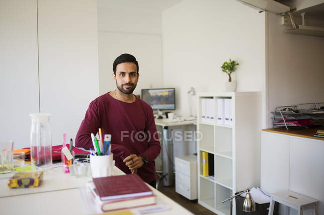 Человек, опирающийся на стол в офисе — стоковое фото