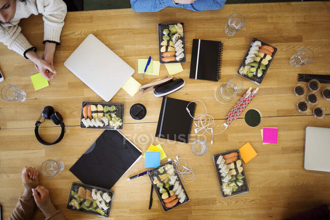 Sushi, notebooks, and laptops on office table — Stock Photo