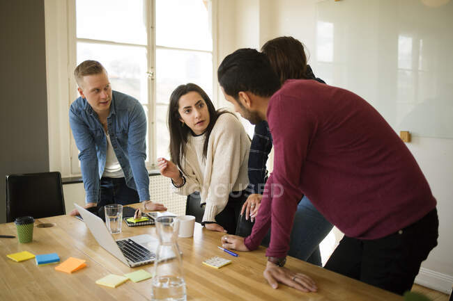 Співробітники збираються навколо ноутбука в офісній конференц-залі — стокове фото