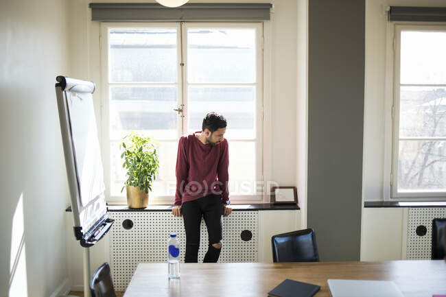 Homme assis sur le rebord de la fenêtre dans le bureau — Photo de stock