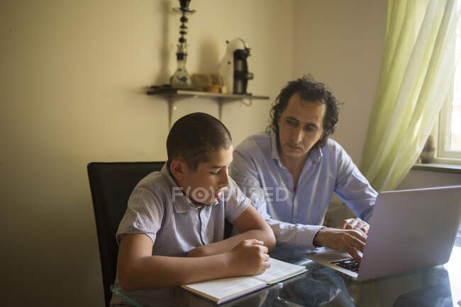 Hombre ayudando a su hijo a estudiar - foto de stock