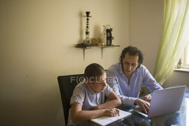 Hombre ayudando a su hijo a estudiar - foto de stock