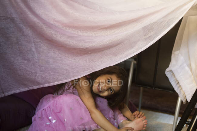 Chica sonriente sentada en el fuerte manta - foto de stock