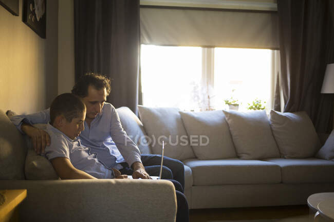 Человек помогает сыну учиться в гостиной. — стоковое фото