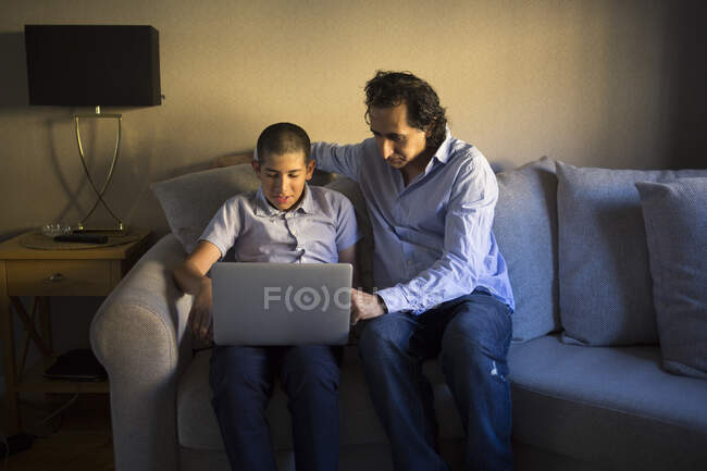 Hombre ayudando a su hijo a estudiar en sala de estar - foto de stock