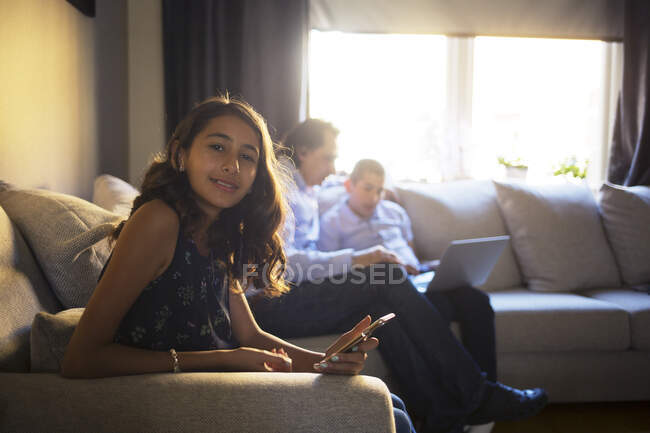 Chica sentada en el sofá con su familia - foto de stock