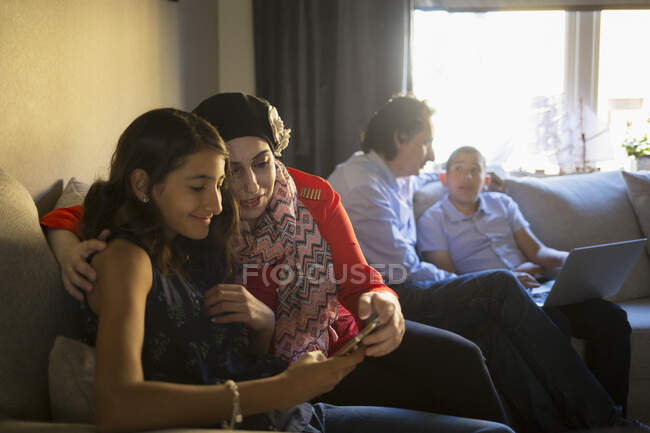 Girl and her mother using smartphone on sofa — Stock Photo
