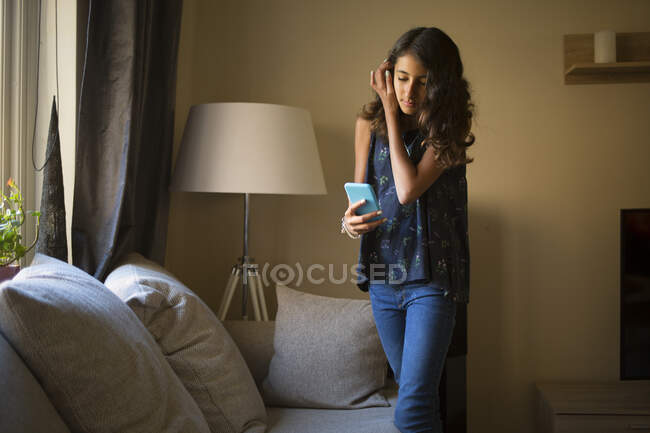 Девушка, использующая смартфон в гостиной — стоковое фото