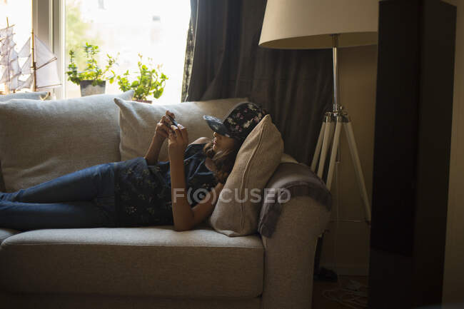 Дівчина використовує смартфон на дивані — стокове фото