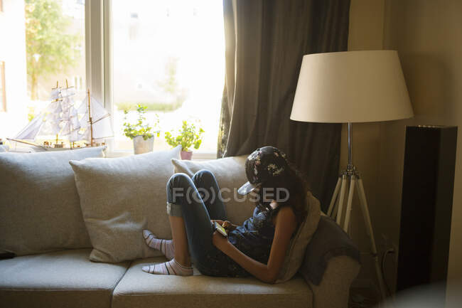 Девушка с помощью смартфона, сидя на диване — стоковое фото
