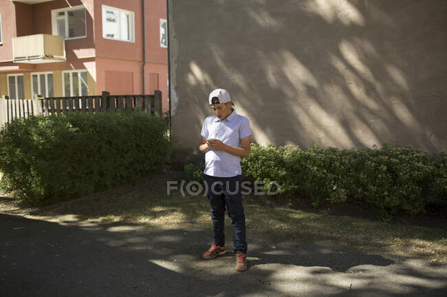 Niño en gorra de béisbol usando smartphone - foto de stock