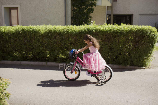 Дівчина їде на велосипеді з тренувальними колесами — стокове фото