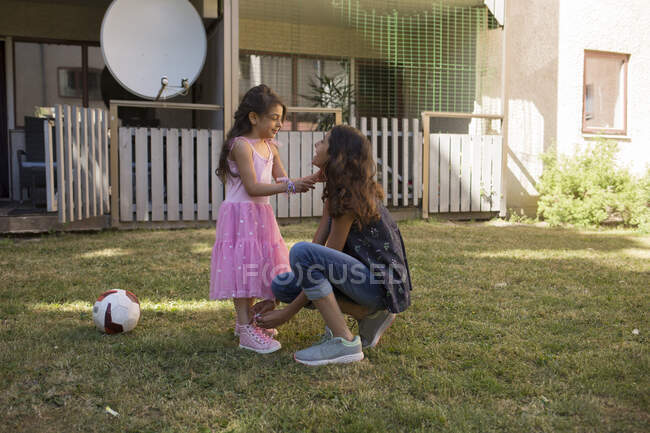 Girl tying her sister's shoe in backyard — Stock Photo