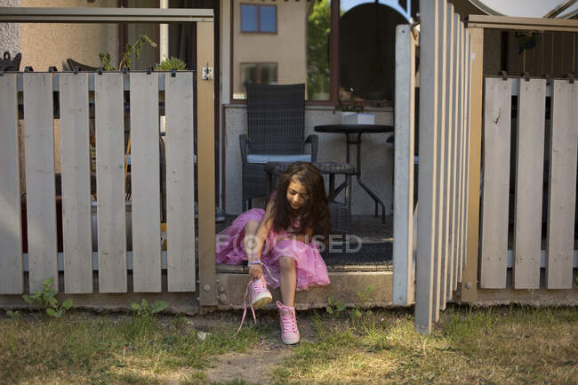 Menina em vestido rosa colocando em sapatos — Fotografia de Stock