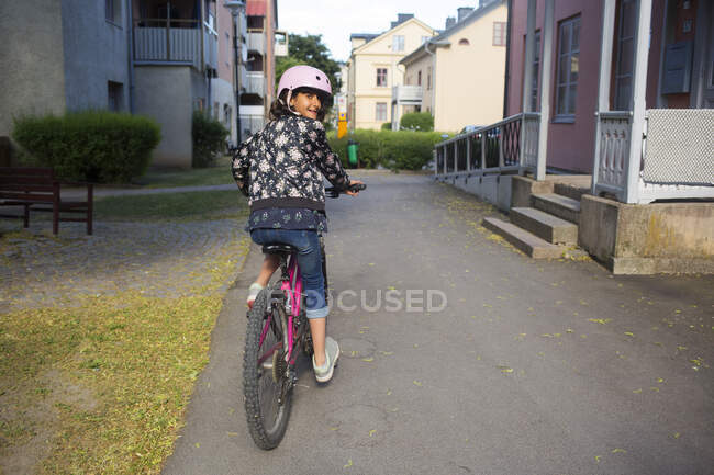 Girl riding bicycle on footpath — Stock Photo