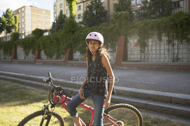 Girl sitting on bicycle in park — Stock Photo
