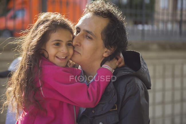 Мужчина целует свою улыбающуюся дочь — стоковое фото