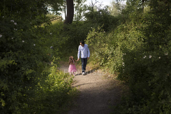 Мужчина гуляет со своей дочерью в парке — стоковое фото