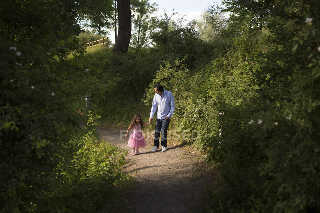 Hombre caminando con su hija en el parque - foto de stock