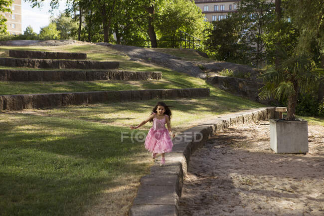 Дівчина в рожевій сукні грає в парку — стокове фото