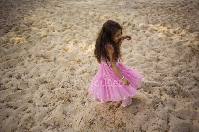 Девушка в розовом платье играет в парке — стоковое фото