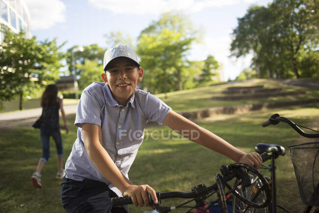 Garoto sorridente com bicicleta no parque — Fotografia de Stock