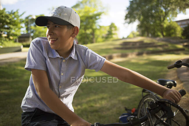 Garoto sorridente com bicicleta no parque — Fotografia de Stock