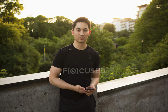 Молодий чоловік зі смартфоном на мосту — стокове фото