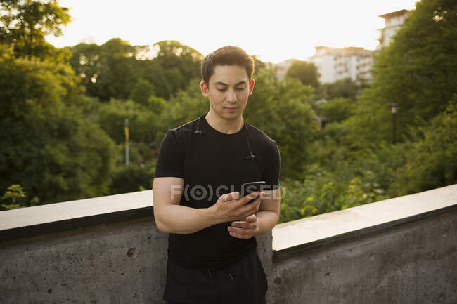 Молодой человек со смартфоном на мосту — стоковое фото