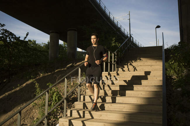 Young man jogging on steps — Stock Photo