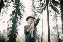 Stylish woman with blonde dreadlocks and henna tattoos posing in woods — Stock Photo