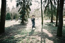 Молода жінка в одязі і капелюсі біжить в сонячному парку — стокове фото