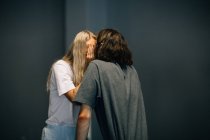 Joven pareja escondiendo beso con palmas - foto de stock