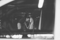 Vue à travers la fenêtre de la voiture pour embrasser couple — Photo de stock
