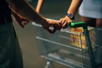 Couple holding hands on shopping cart — Stock Photo