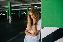 Blondes Mädchen lehnt an Säule und blickt in Kamera — Stockfoto