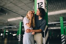 Young couple bonding by column at parking — Stock Photo