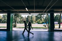 Silhouettes of couple walking at parking on background of sunlit street — Stock Photo