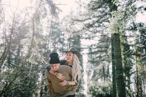 Elegante ragazza con dreadlocks abbracciando ragazzo da dietro alla scena della foresta — Foto stock