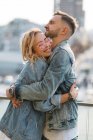 Szenischer Blick auf umarmendes junges erwachsenes Paar gegen modernes Stadtbild — Stockfoto