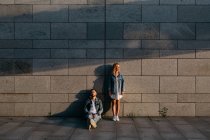 Молодая взрослая пара в повседневной одежде возле серой стены — стоковое фото