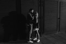 Vista laterale di baciare giovane coppia adulta vicino persiane di legno, in bianco e nero — Foto stock