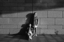 Молодая взрослая пара в повседневной одежде возле серой стены, черно-белая — стоковое фото